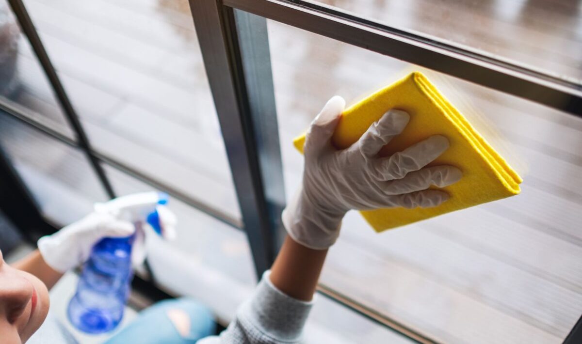 A young woman wearing protective glove cleaning the window for housework concept